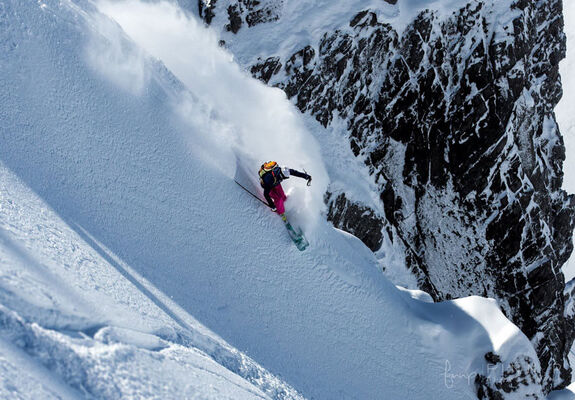 A skier descends a deep snow slope off-piste