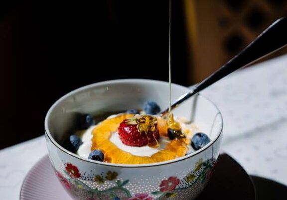 A bowl filled with yogurt, fruit and honey, that's how you shoul start your day