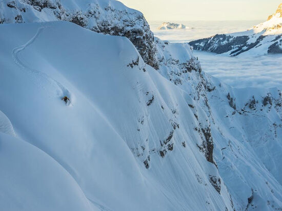 Ein Skifahrer bahnt sich seinen abenteuerlichen Weg eine Bergseite hinab durch den Tiefschnee