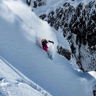 A skier descends a deep snow slope off-piste