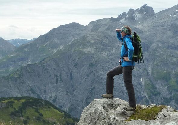 Frau steht auf Berg und schaut in die Ferne