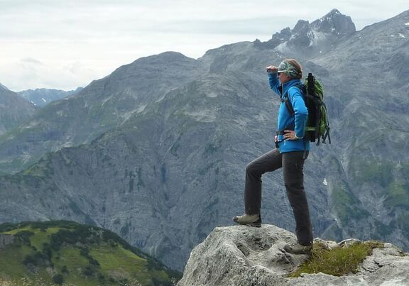 Frau steht auf Berg und schaut in die Ferne