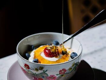 A bowl filled with yogurt, fruit and honey, that's how you shoul start your day