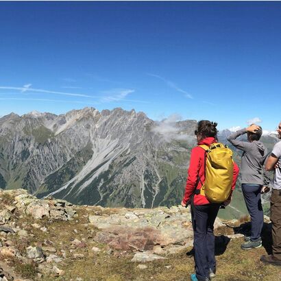 Drei Menschen bestaunen den Ausblick auf die Berge